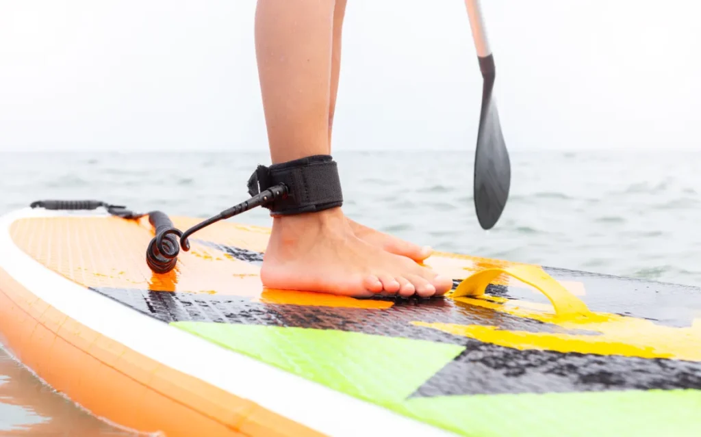 close up of a person standing on a SUP with safety leash around ankle